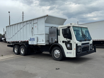 Mack LR64 BE dump truck in serviceable condition showing dump bed and front cab with electric/digital components in a showroom lot.