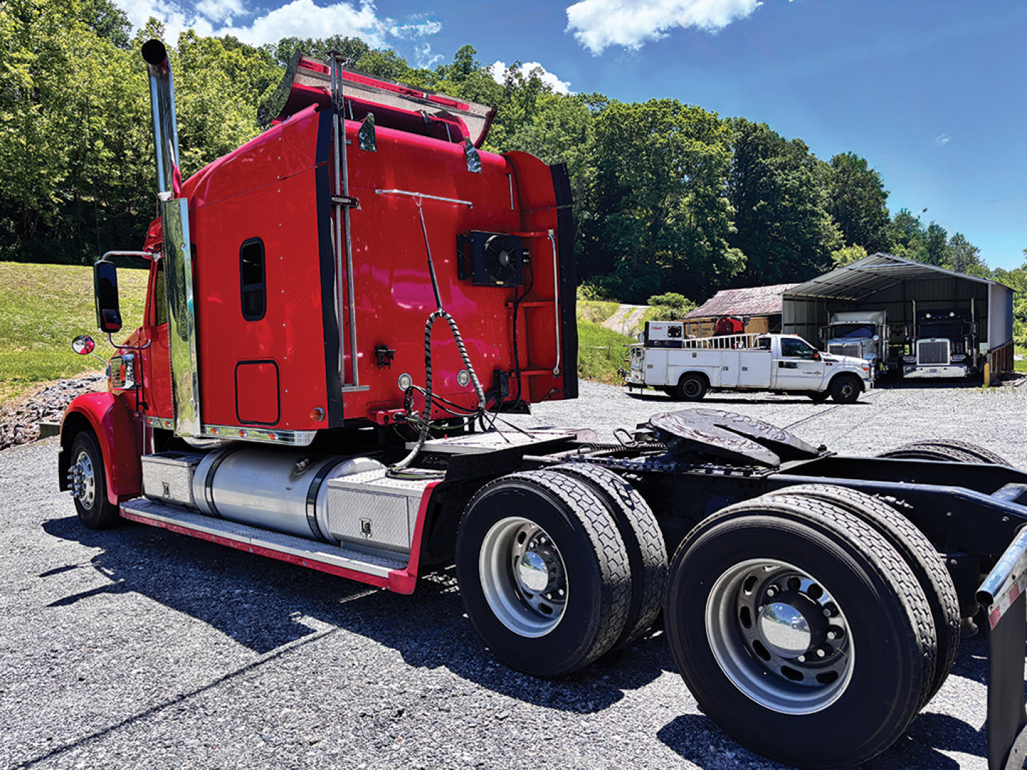 Red Freightliner Coronado sleeper truck cab side rear view showing chassis and tandem axles.