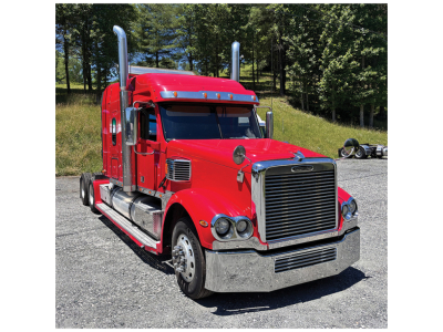 Truck cab showing a red 2013 Freightliner Coronado conventional sleeper with chrome grille, dual exhaust stacks, and side steps.