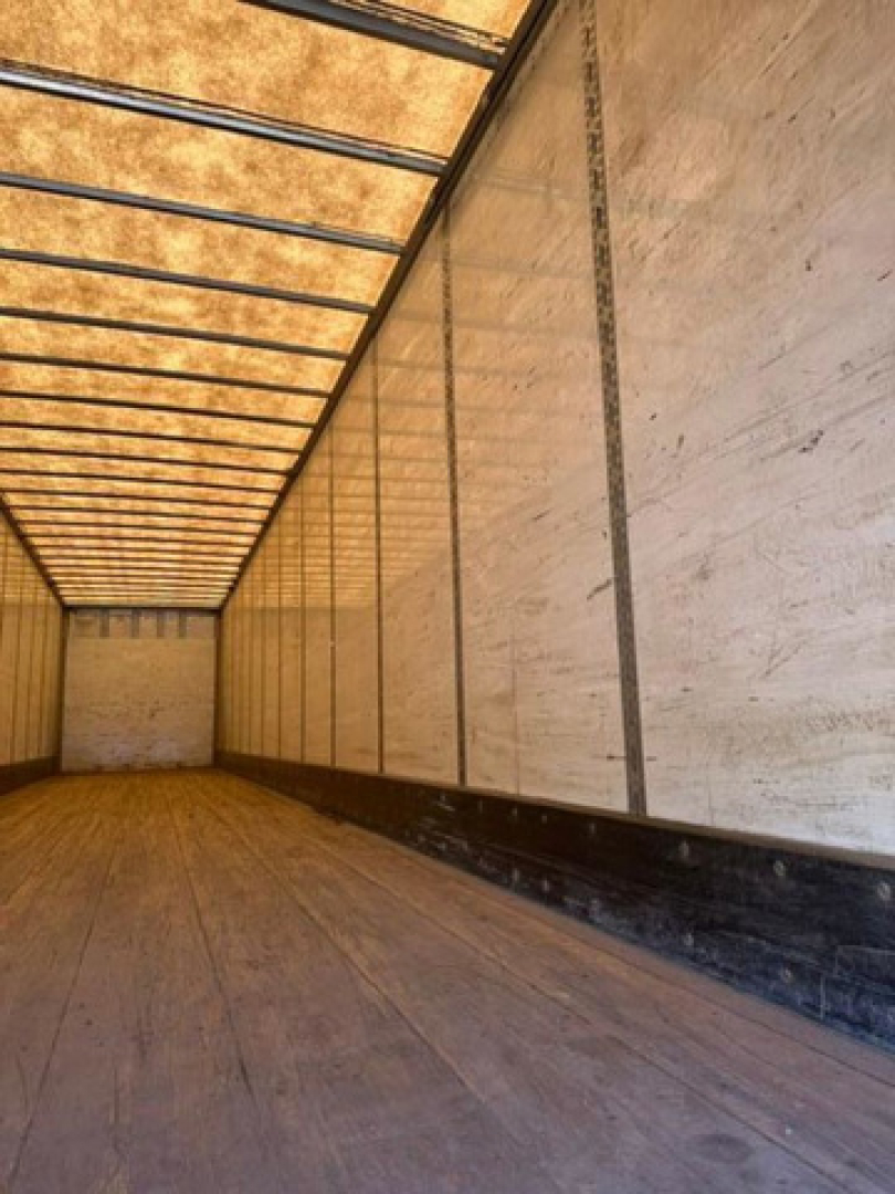 Wabash trailer interior view showing wooden floor and side walls with metal support rails along top; empty cargo area.