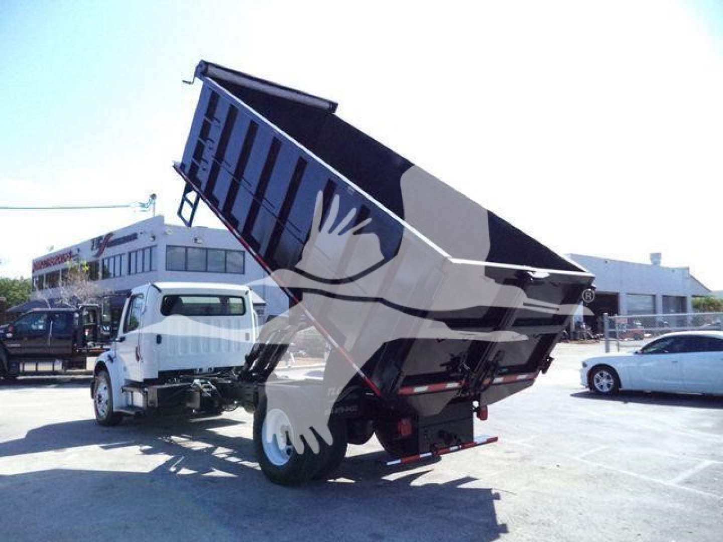 Dump truck bed in raised position on a 2017 Freightliner M2 106 dump truck, with surrounding lot and other vehicles.