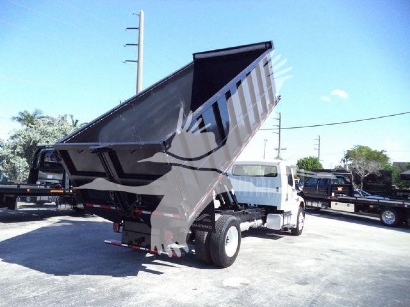 Dump truck bed tilted to show dumping mechanism on a Freightliner M2 106 in service.