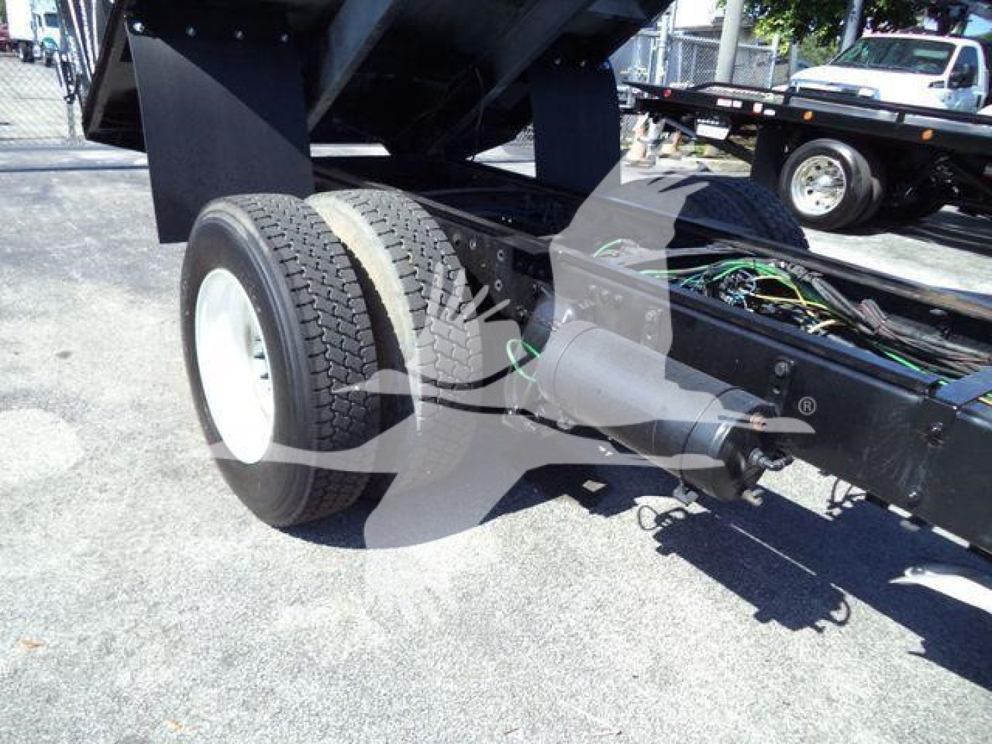Freightliner M2 106 chassis showing rear wheels and undercarriage with wiring visible; dump bed raised.
