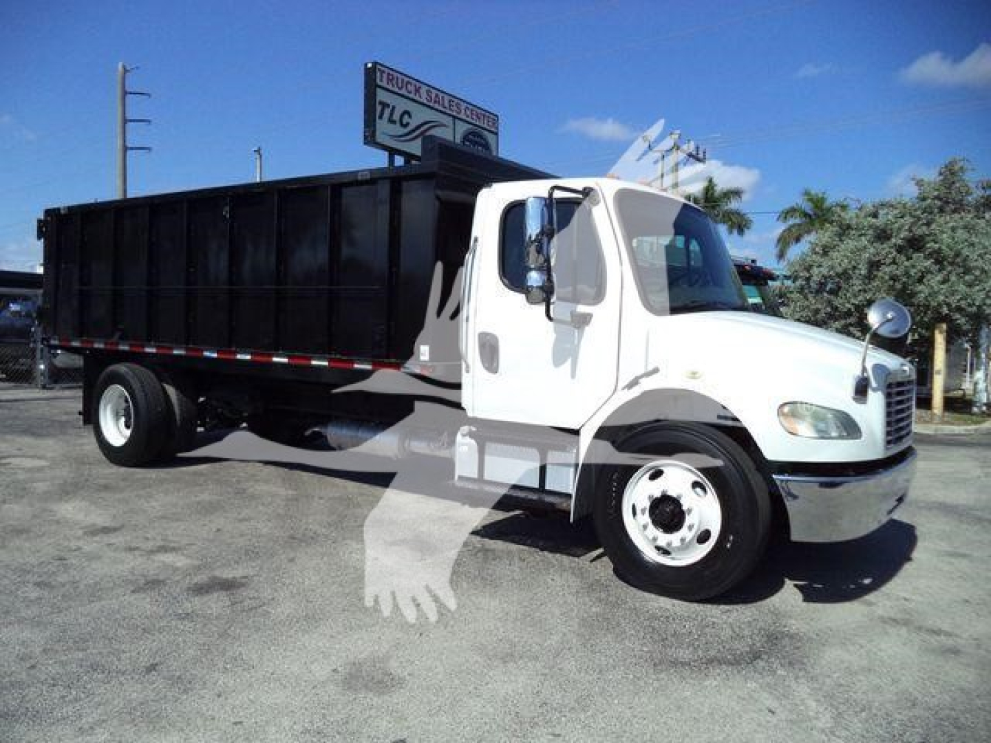 Dump truck in service showing Freightliner M2 106 cab and black dump bed with side rails.