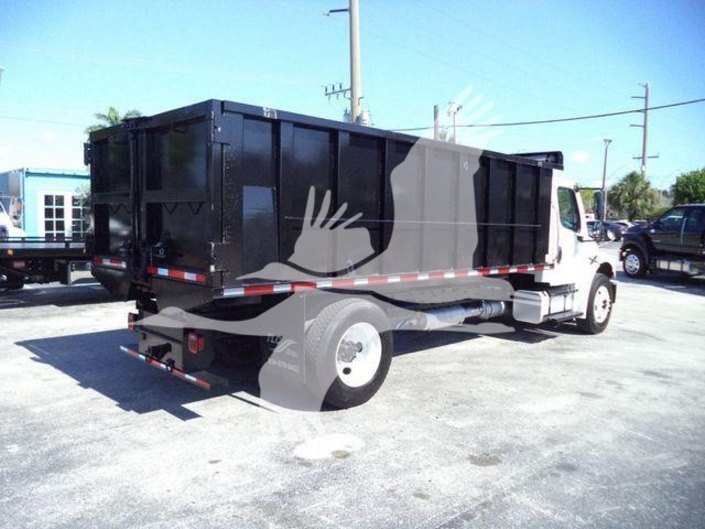 Dump truck bed of a Freightliner M2 106 with black dump body, rearview showing tail lights and reflective stripes.