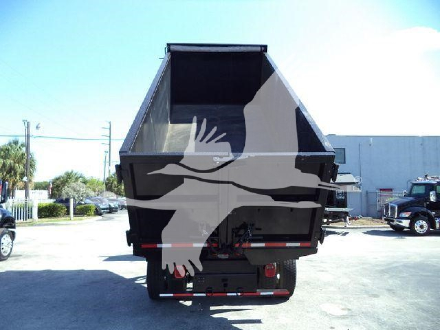 Truck dump bed of a Freightliner M2 106 with empty hopper and rear view showing dump hydraulics and bumper.
