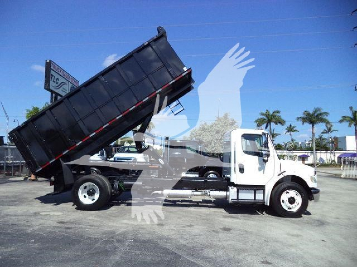 Freightliner M2 106 dump truck tilting bed showing raised cargo bed and white cab.