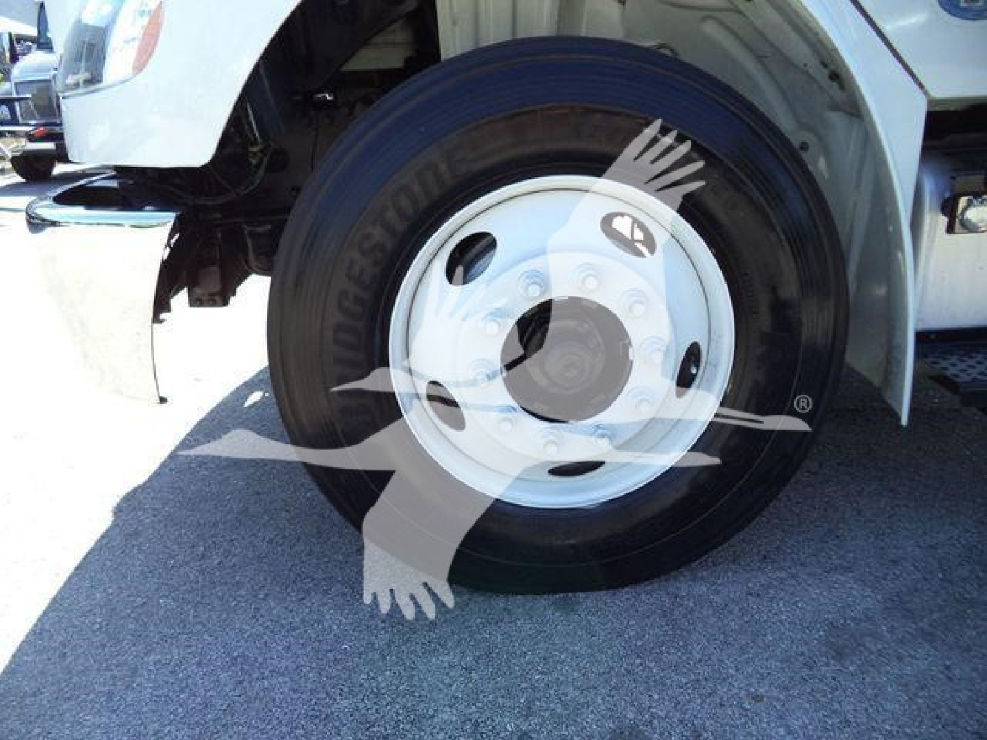 Front wheel of a Freightliner M2 106 dump truck showing wheel, tire, and fender area.