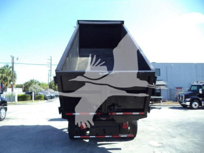 Truck dump bed of a Freightliner M2 106 with empty hopper and rear view showing dump hydraulics and bumper.