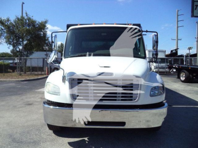 Truck front view showing Freightliner M2 106 grille and chrome bumper. Windshield with side mirrors, headlights, and a white cab. No visible text other than design elements.