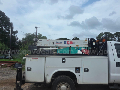Service truck bed with utility storage compartments and a mounted crane crane arm in white and silver Ford F-350 utility body