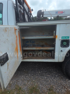 Ford F-350 utility truck side compartment with open shelves showing storage drawers and rust marks