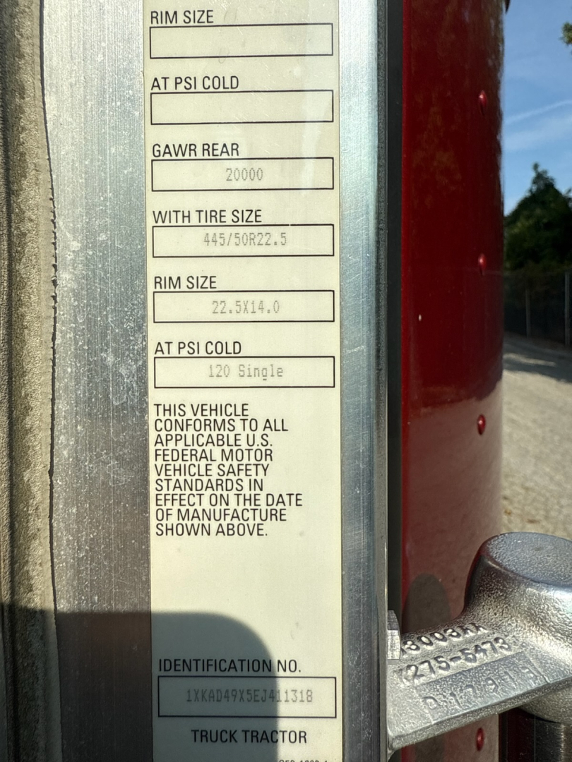 Label on Kenworth truck door jamb with tire size and pressure fields and VIN area. Visible text includes: RIM SIZE, AT PSI COLD, GAWR REAR 20000, WITH TIRE SIZE 445/50R22.5, RIM SIZE 22.5X14.0, AT PSI COLD 120 Single, THIS VEHICLE CONFORMS 