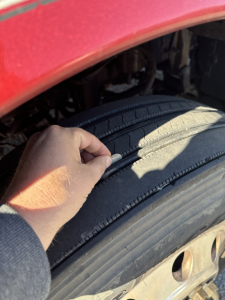 Tire tread close-up on Kenworth T660 wheel well with a hand pressing the tire sidewall.