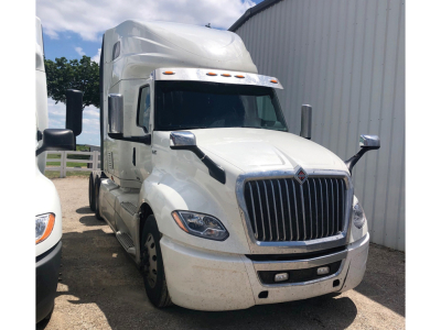International LT625 truck in white, front/driver side view, chrome grille, large side mirrors, sleeper cab, daytime outdoor lot.