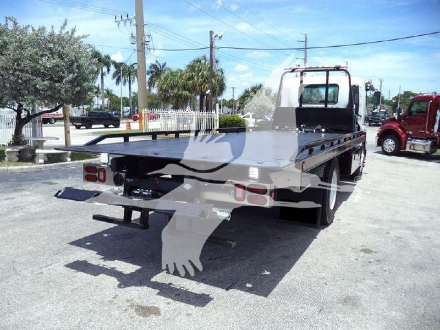 Flatbed tow truck chassis with truck cab, rear view shows flatbed and towing equipment.