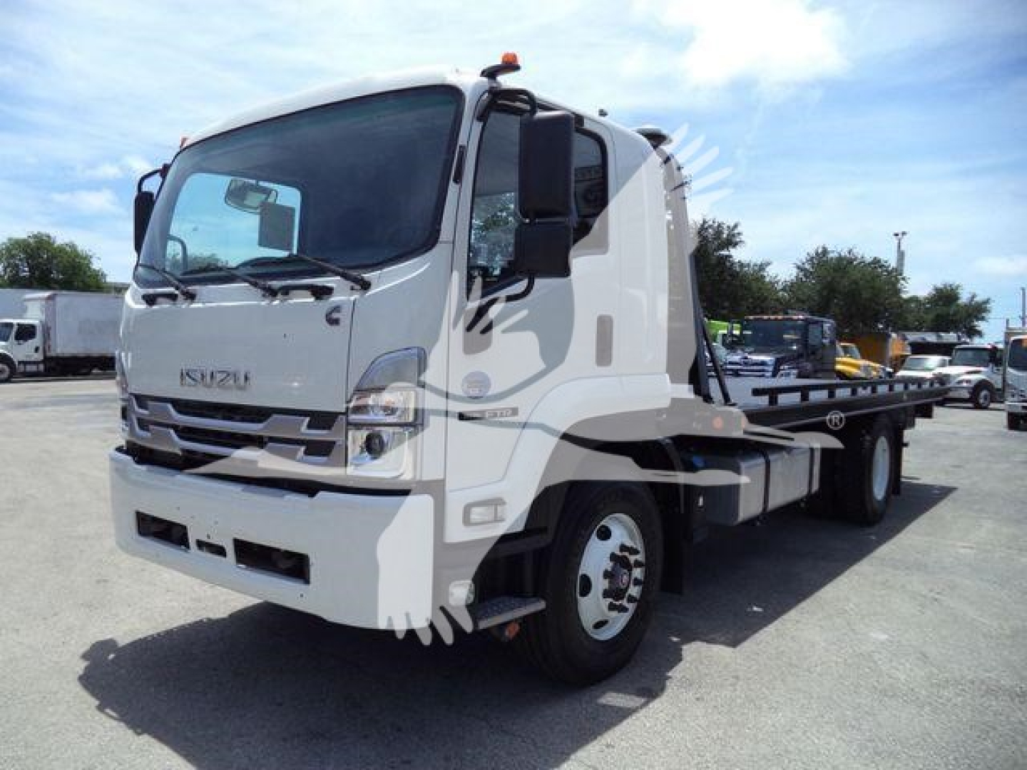 Isuzu tow truck with flatbed, front cab visible, dashboard and door. No text clearly legible on the vehicle aside from generic Isuzu styling.