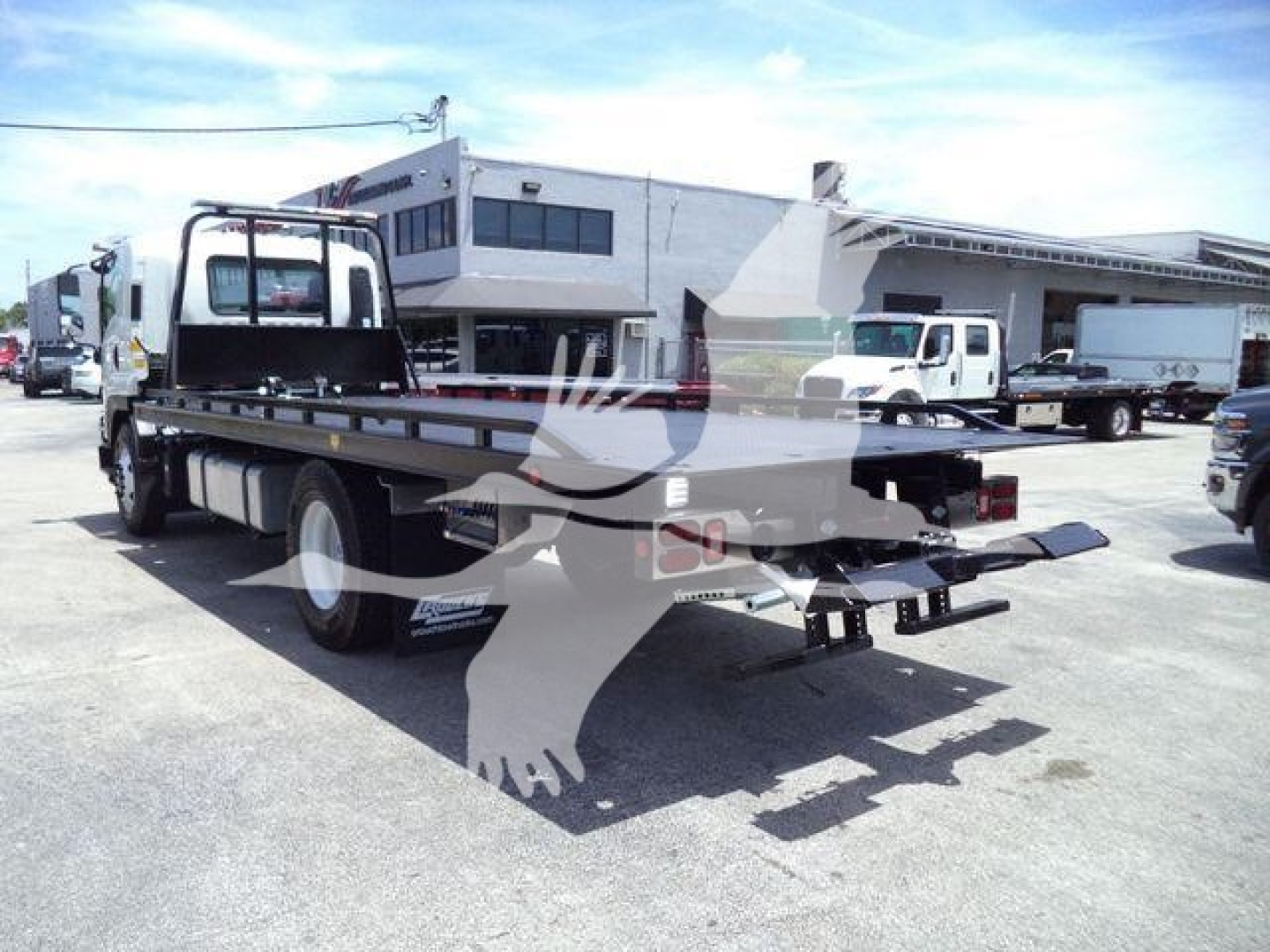 Isuzu FTR rollback tow truck rear view showing flatbed and rear equipment.