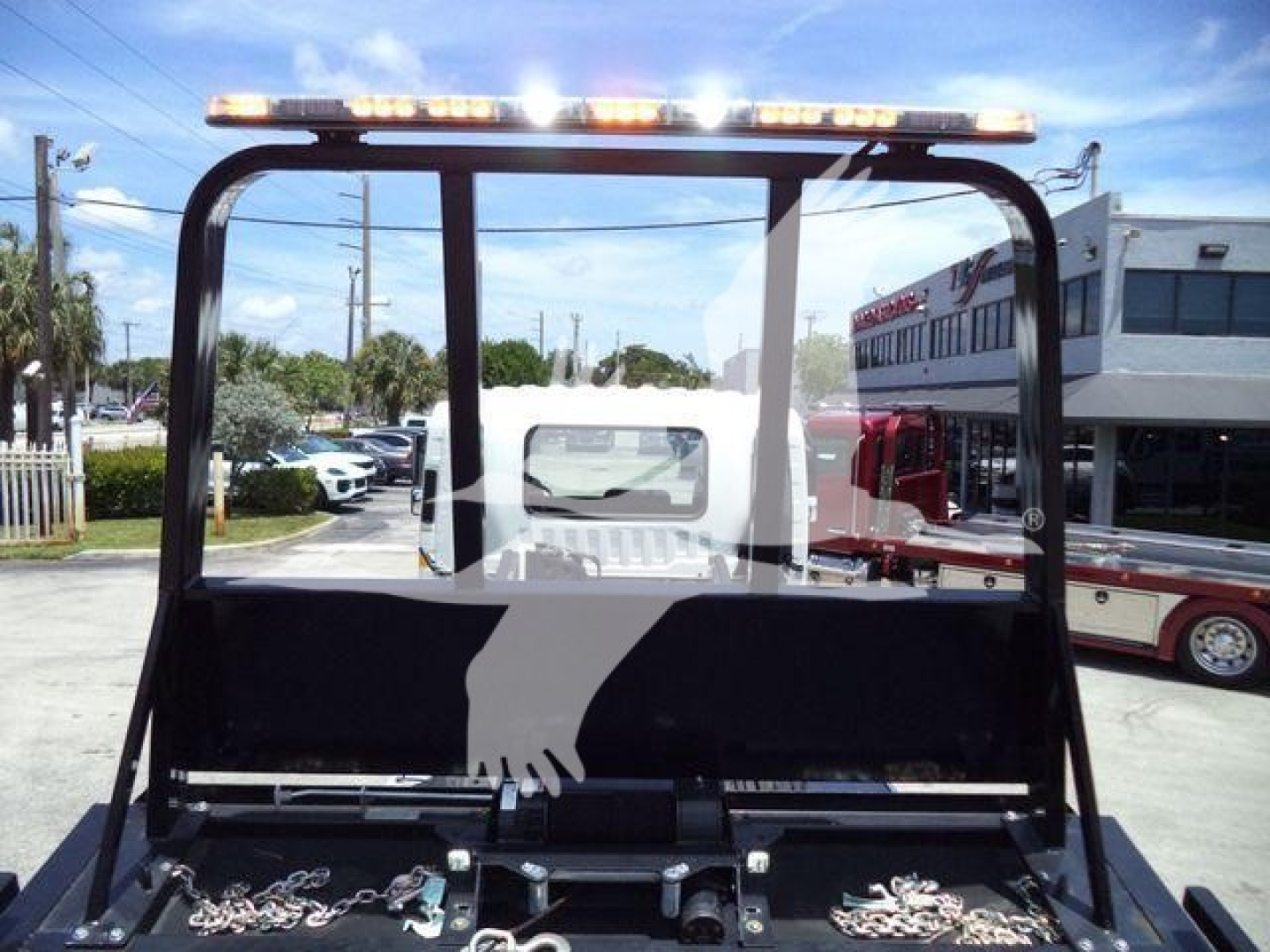 Trucks equipment image showing a Isuzu FTR rollback truck cab back view with a light bar on the top, rear frame and hooks, and a towing apparatus visible in the bed.