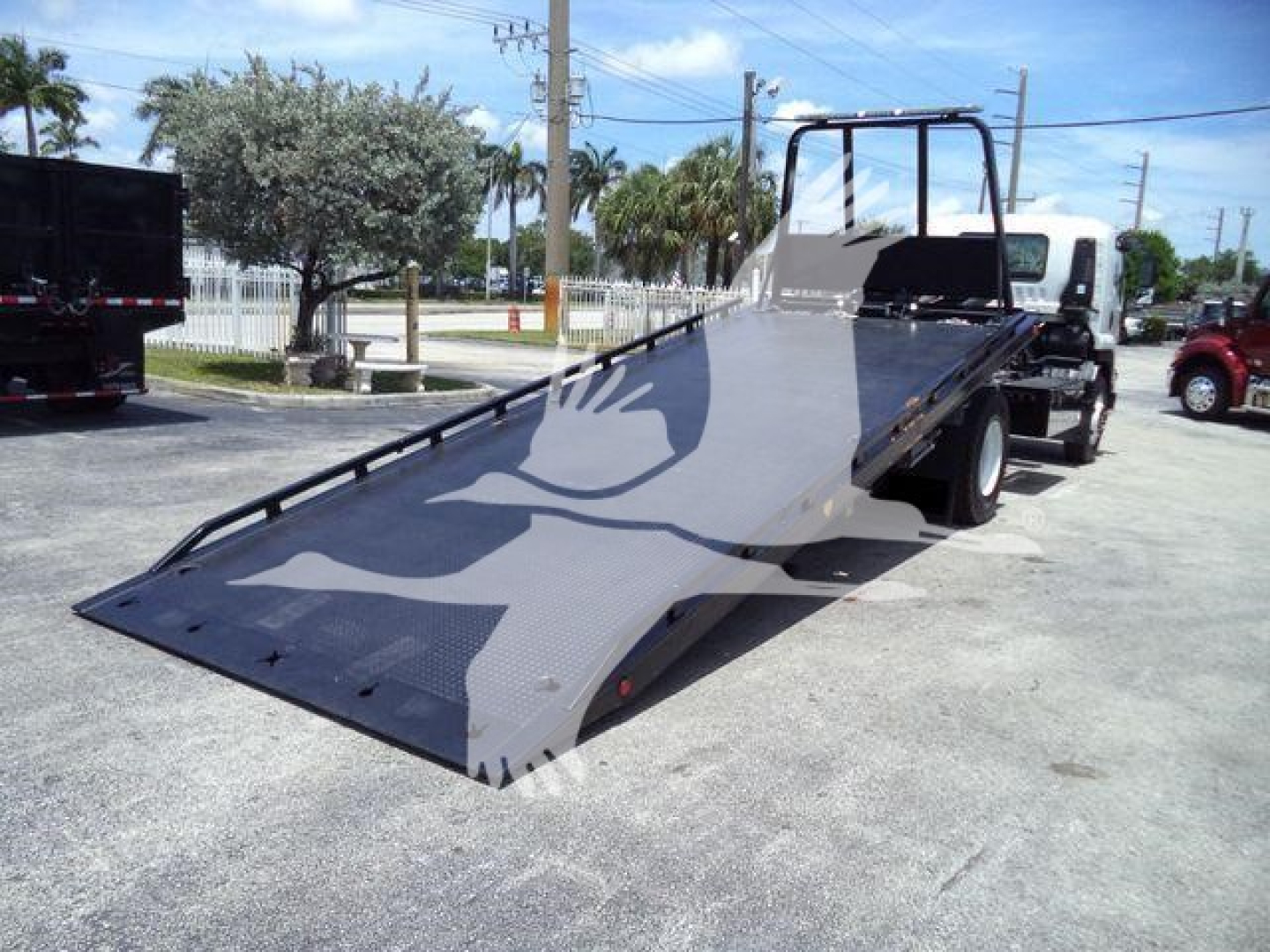Isuzu FTR rollback truck with flatbed ramp extended, view shows towing equipment and hydraulic tilt surface.