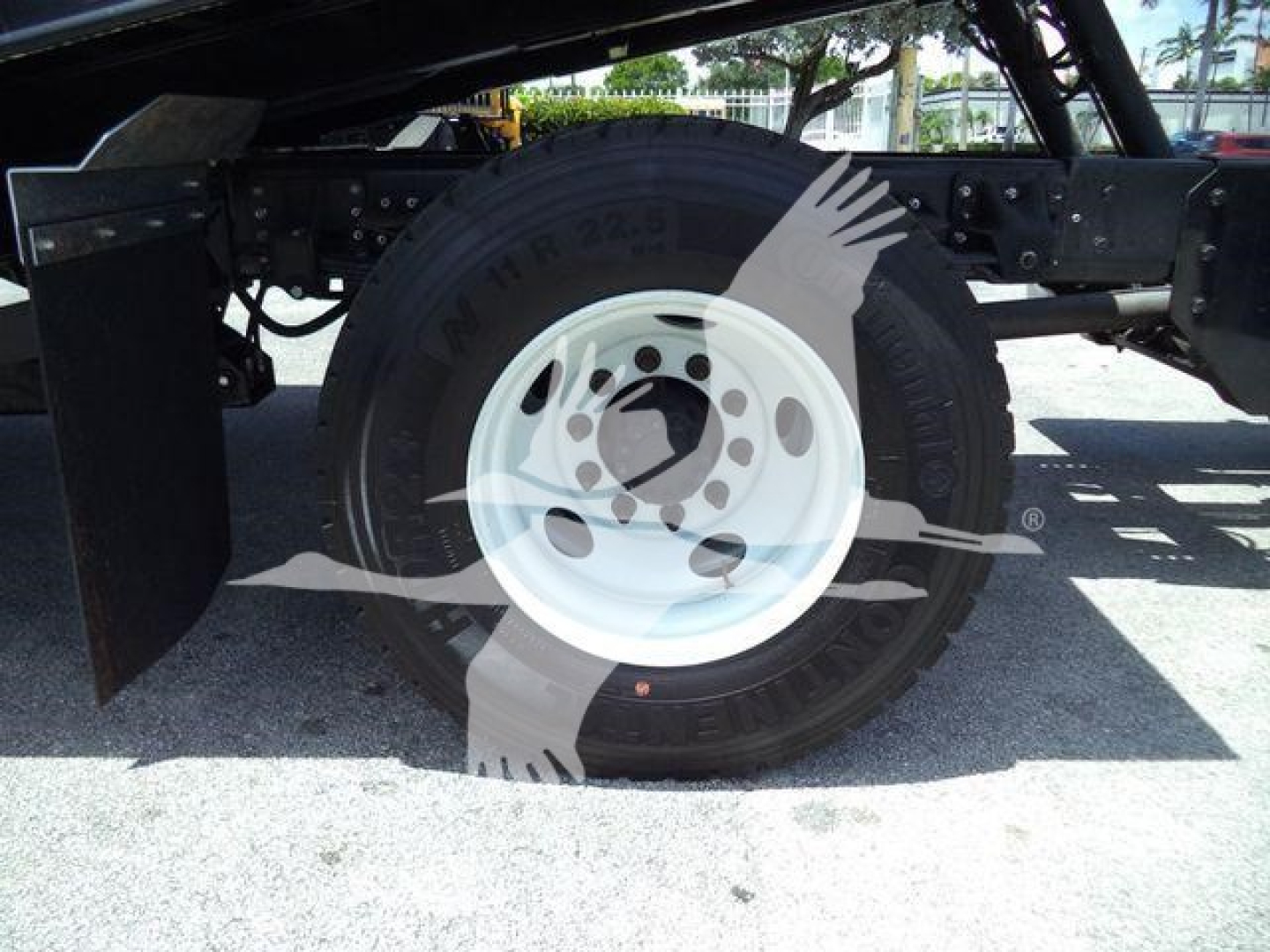 Isuzu FTR truck wheel and suspension visible with white steel rim and heavy-duty tire.