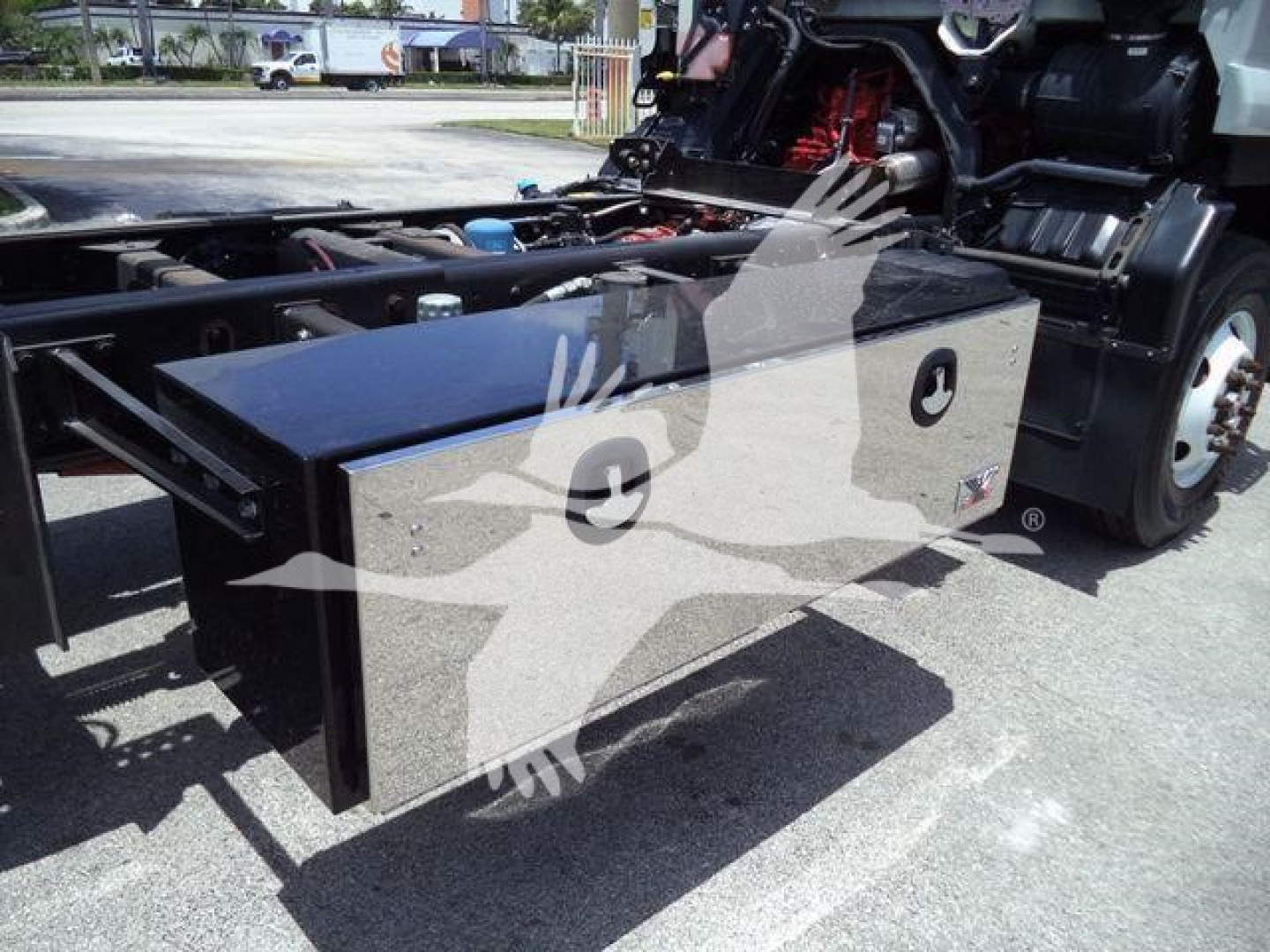 Isuzu truck with a large rectangular metal cargo box mounted near the chassis, visible cab and wheels in background.