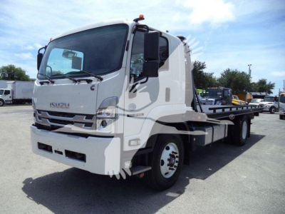 Isuzu tow truck with flatbed, front cab visible, dashboard and door. No text clearly legible on the vehicle aside from generic Isuzu styling.