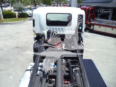 Isuzu truck cab chassis rear view with hydraulic lines and frame, empty cargo area; visible components include engine bay, wiring, and framework.