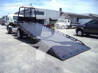 Isuzu FTR tow truck with a lowered flatbed and hydraulic winch, side view showing ramp and deck in serviceable condition.
