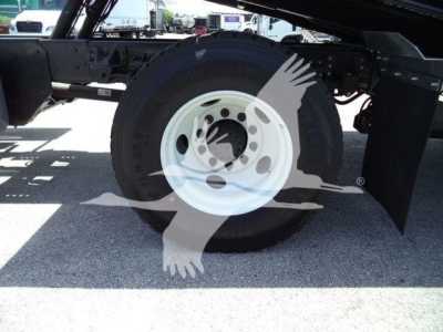 Isuzu FTR truck chassis showing front wheel with white steel rim and black tire; undercarriage and suspension visible.