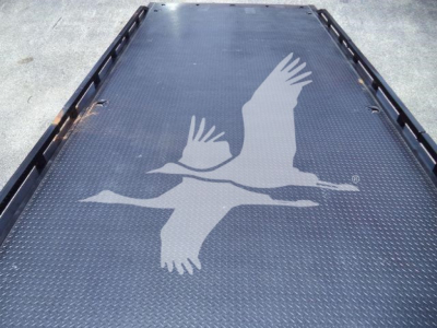 Isuzu logo graphic on a metal truck bed surface with diamond plate pattern