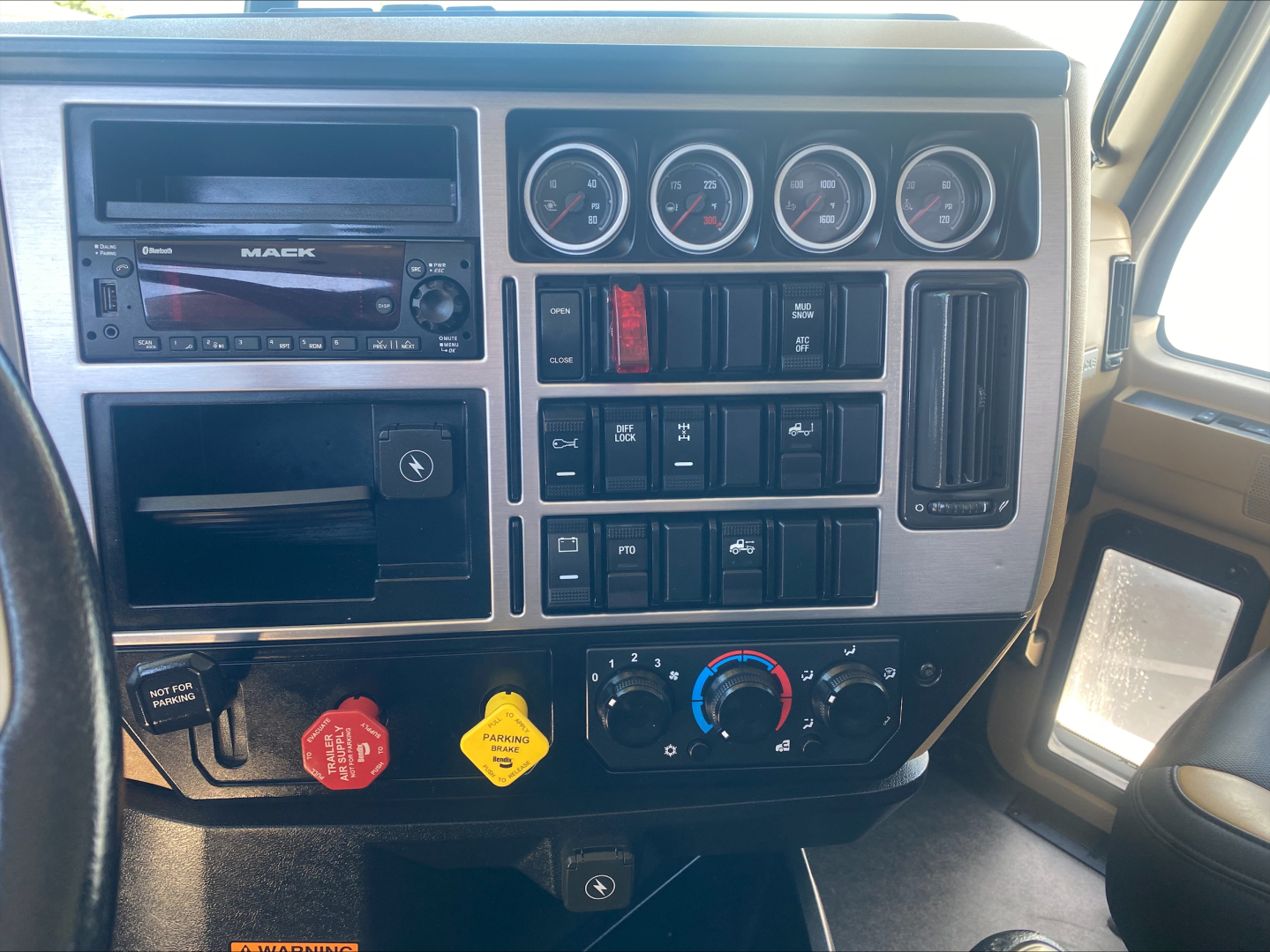 Mack PI64T truck instrument cluster and dashboard controls showing gauges, stereo, switches, and climate controls.