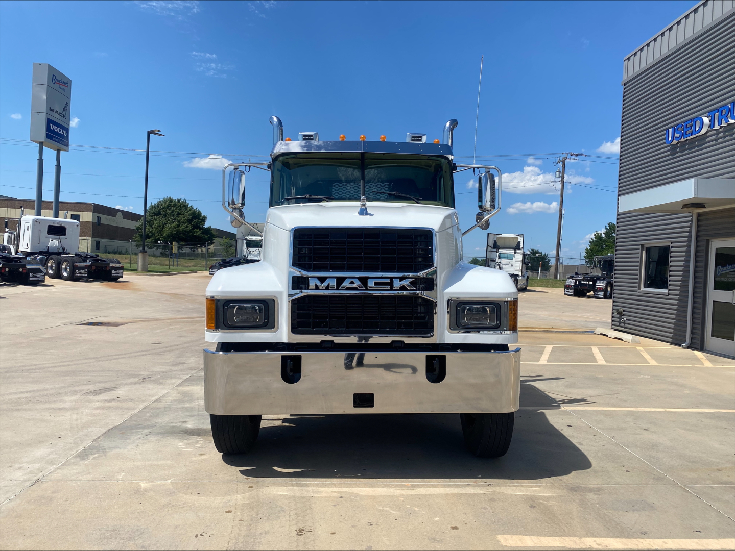 Mack PI64T truck front view showing bold grille with MACK emblem, rectangular headlights, chrome bumper, roof lights, and side mirrors.