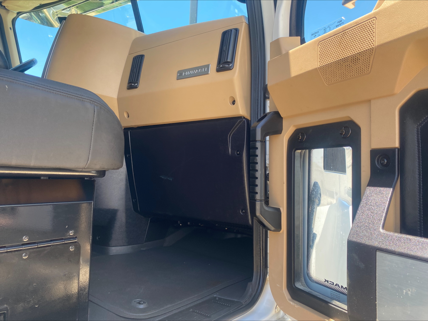 Mack PI64T truck interior showing tan and black cabin panels with storage compartment and door sill; visible label reads PIONEER? not legible.