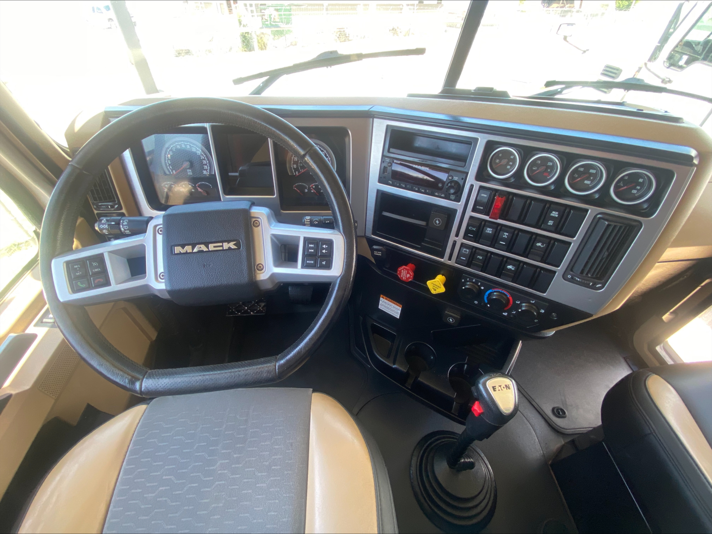 Mack PI64T truck cab interior showing steering wheel, dashboard gauges, gear shifter, and control panel.