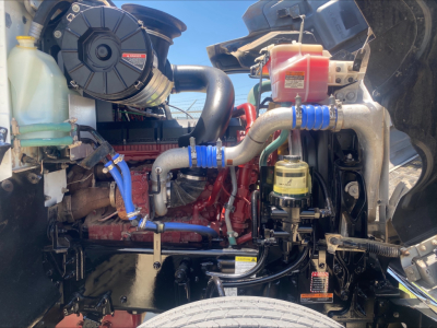 Mack PI64T engine bay showing cooling reservoir, blue hoses, red engine block, yellow oil filter, and intake components.