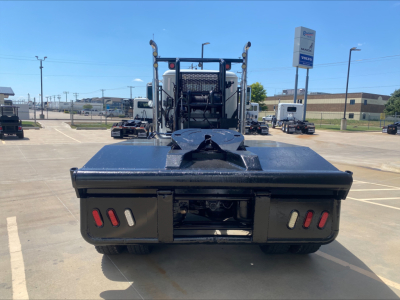 Front/rear angle of a Mack PI64T heavy-duty truck with a winch, showing rear tail area and bumper with two red LED lights on each side, flatbed, and towing equipment.