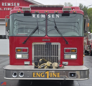 Fire truck front view showing REMSEN lettering on windshield, DARLEY badge, grille, and ENG1NE on bumper; red cab with wavy hoses and chrome bumper.