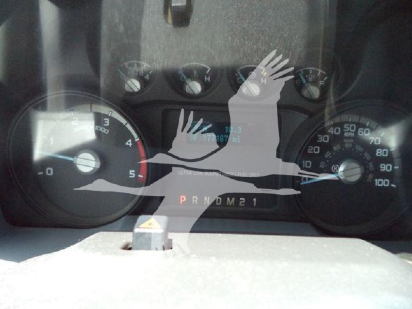 Dashboard view of a 2011 Ford F-450 showing speedometer and tachometer with gear indicator PRNDM21 and odometer reading."
