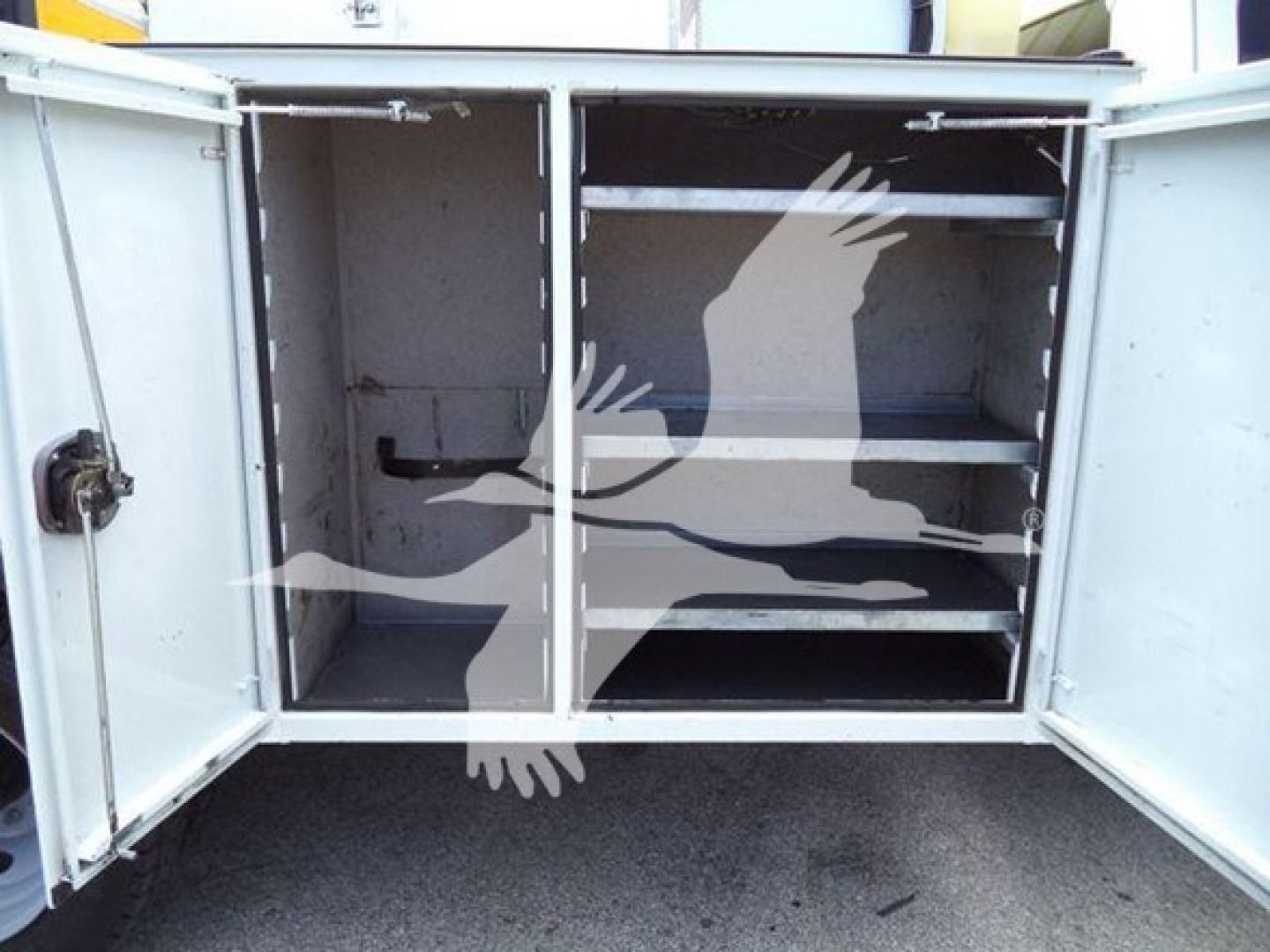 Ford F-450 service bed with metal cabinet doors open showing two shelves.