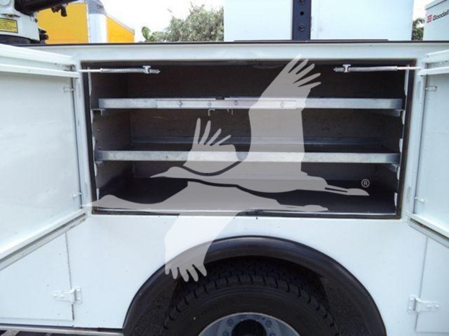 Ford F-450 service body rear storage compartments with open doors showing adjustable shelves and tool trays.