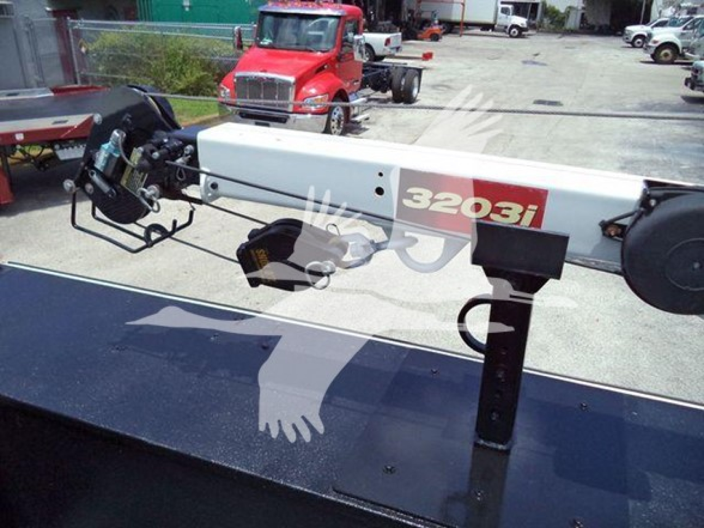 Forklift boom crane attachment labeled 3203i mounted on a truck bed, with hydraulic components and control levers visible.