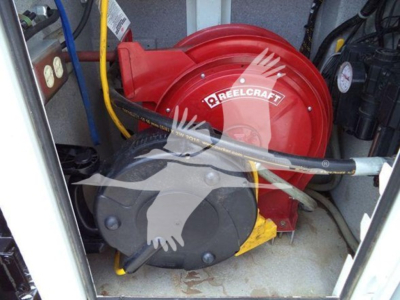 Hose reel and engine bay of a service vehicle with a red Darecraft hose reel and black compressor unit, visible labels and cables.
