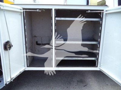 Ford F-450 service bed with metal cabinet doors open showing two shelves.