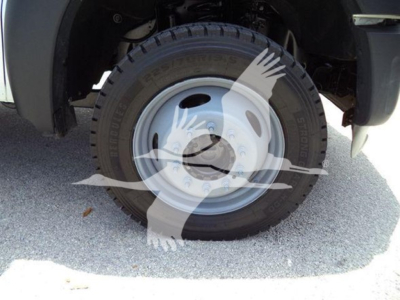 Wheel and tire assembly of a Ford F-450 dual rear wheel with steel rim and exposed lug nuts, partial fender and tire sidewall visible.