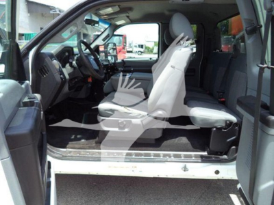 Ford F-450 XLТ interior cab view showing front seats, steering wheel, and dashboard; driver door open; light gray upholstery and vinyl floor in-service truck.