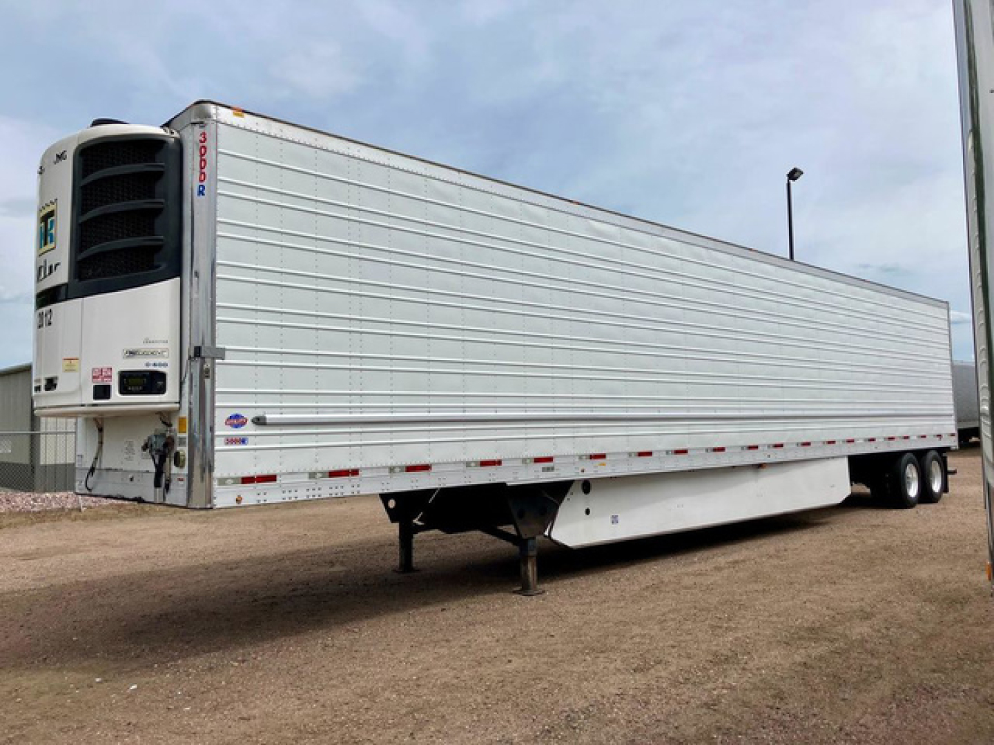 Trailer side view showing a 2020 utility reefer refrigerated trailer with Thermo King unit at front, metal ribbed walls, landing gear, and tandem rear wheels.