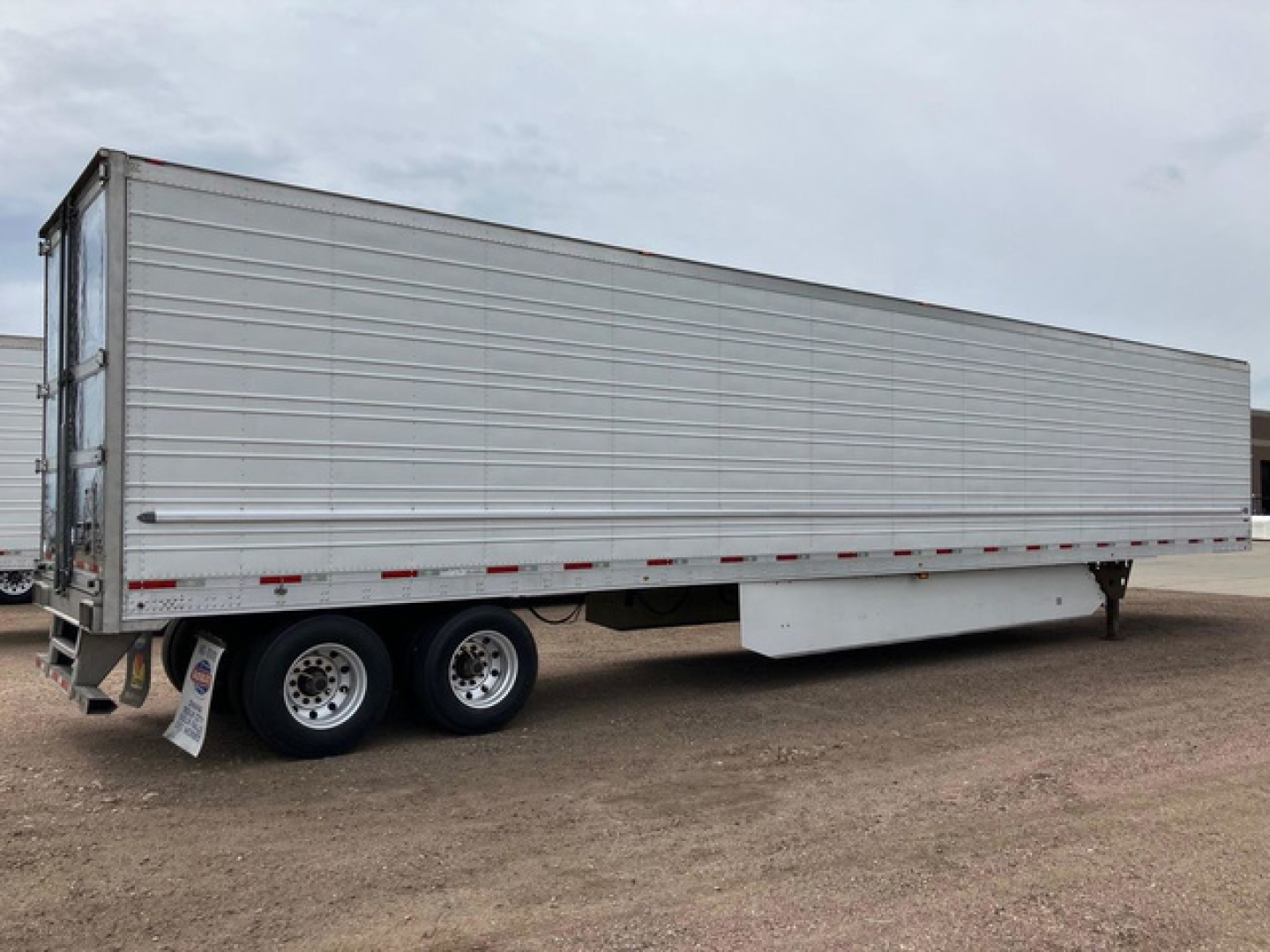 Triple-axle refrigerated trailer showing exterior corrugated aluminum body and rear doors.