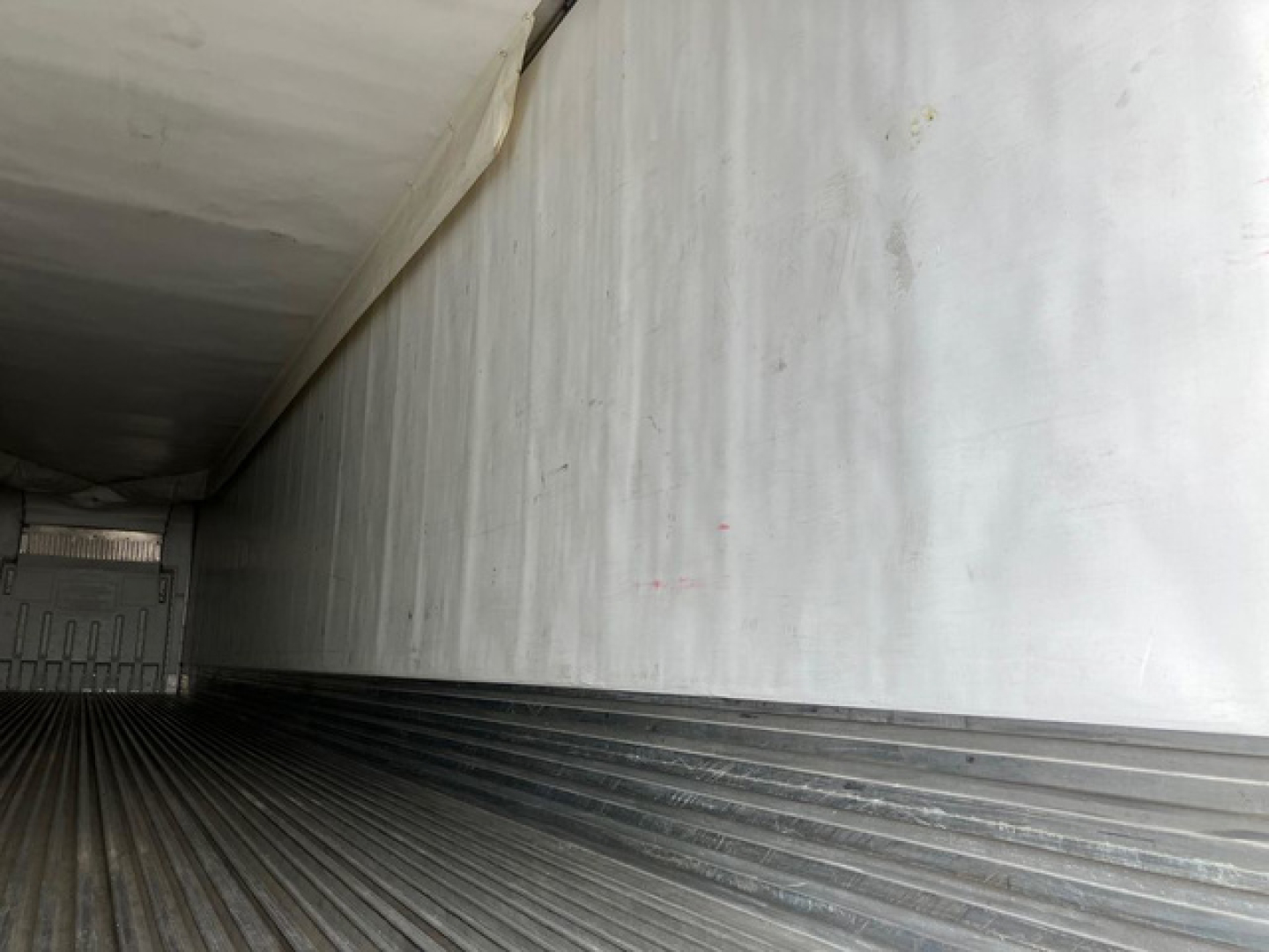 Trailer interior cargo area with insulated walls and ribbed metal floor.