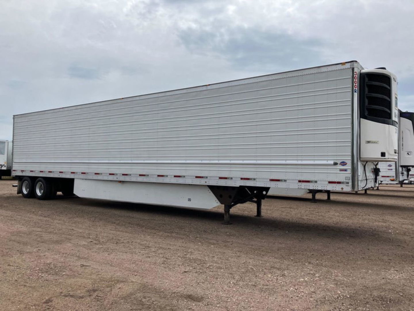 Trailer side view showing a 2020 utility reefer trailer with silver ribbed walls, refrigeration unit at front, tandem axles at rear, and landing gear visible.